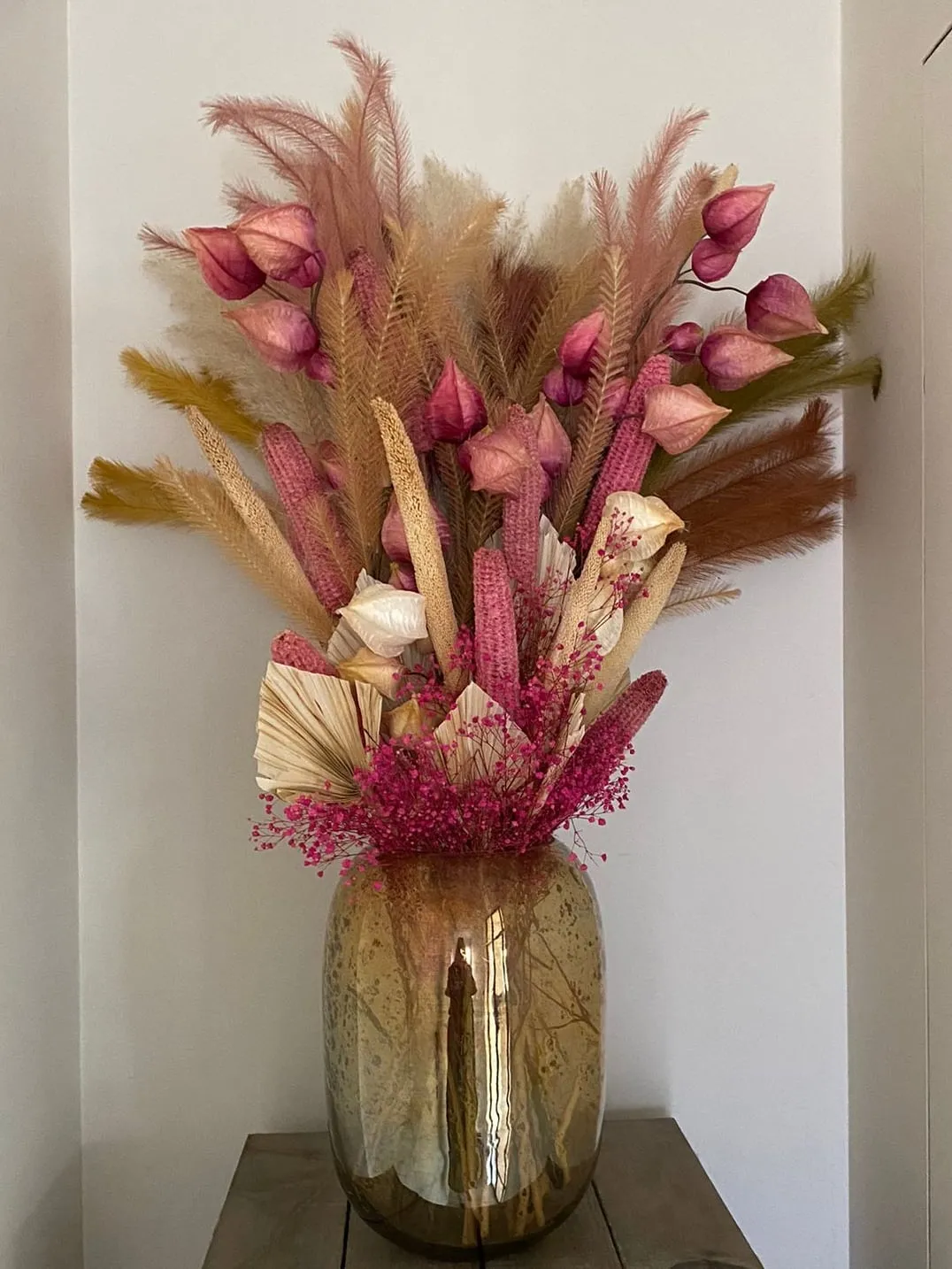 Droogbloemen in roze en oker in een gouden vaas