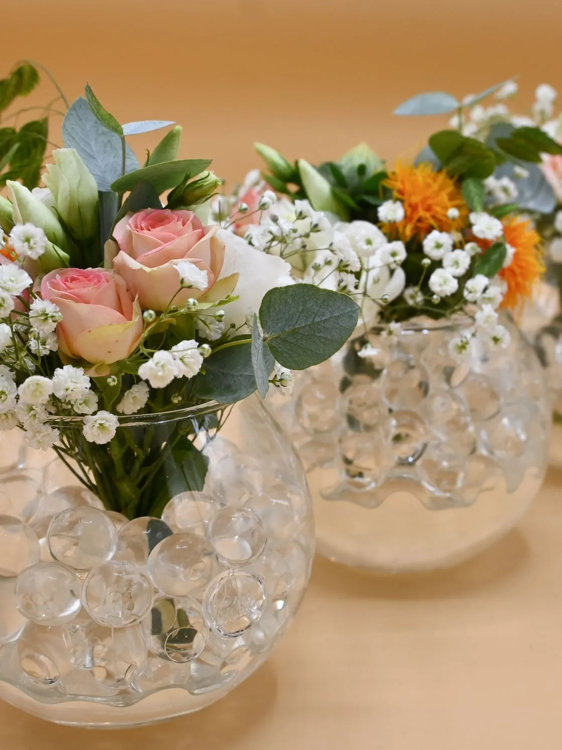 Bolvazen met roze rozen, eucalyptus en gipskruid op een houten tafel